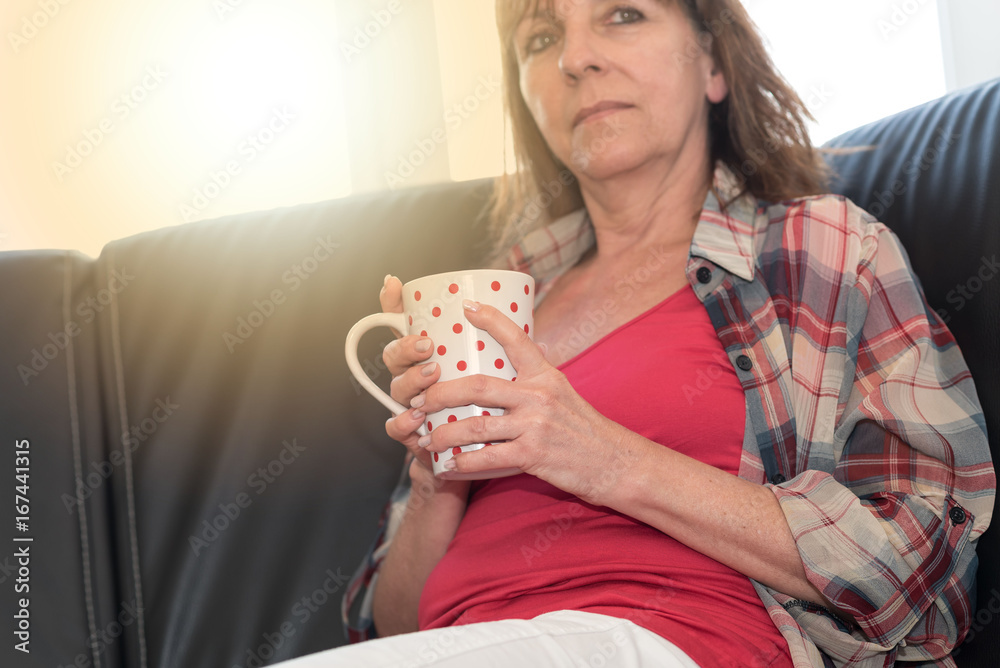 Thoughtful woman sitting on sofa, light effect Thoughtful woman sitting on sofa, light effect