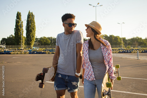 portrait of beautiful couple with skateboard, posing during sunrise  photo