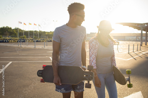 portrait of beautiful couple with skateboard, posing during sunrise  photo