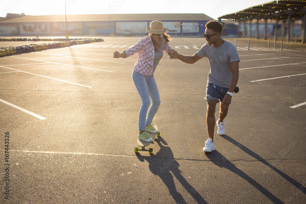 Fototapeta premium Young couple riding skateboard during sunrise 