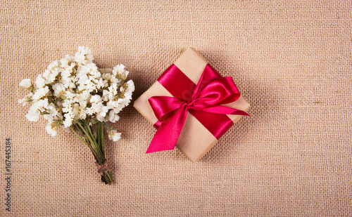 Gift box with a red bow and flowers. Festive concert. Copy space