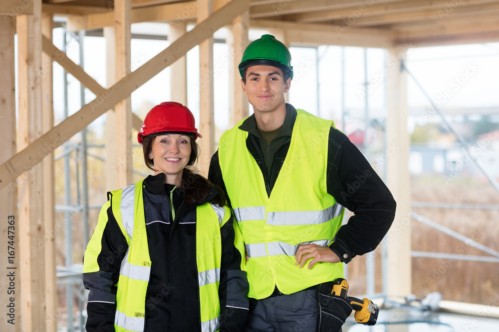 Confident Carpenters Wearing Reflective Jackets At Site Confident Carpenters Wearing Reflective Jackets At Site