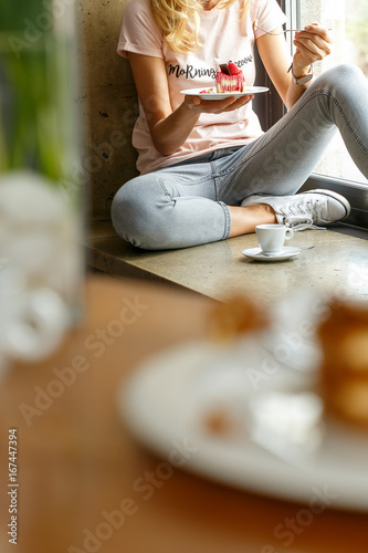 Young girl eating small raspberry cake in Italian restaurant.