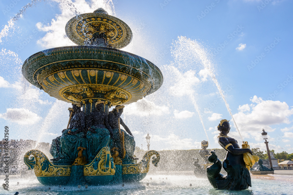 The Fountain of the Rivers in the Concorde square in Paris, France, with statues of Nereids and Tritons holding golden fishes spitting water to the upper basin.