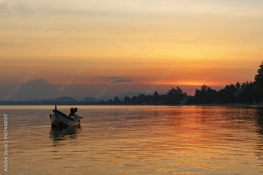 Orange sunset on the sea with a small boat, Thailand