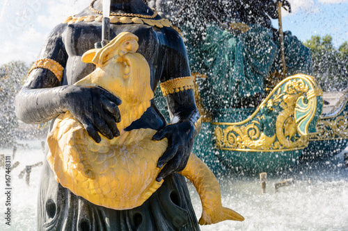 Close-up view of the Fountain of the Seas in the Concorde square in Paris, France, with a statue of a Nereid holding a golden fish spitting water to the upper basin. photo