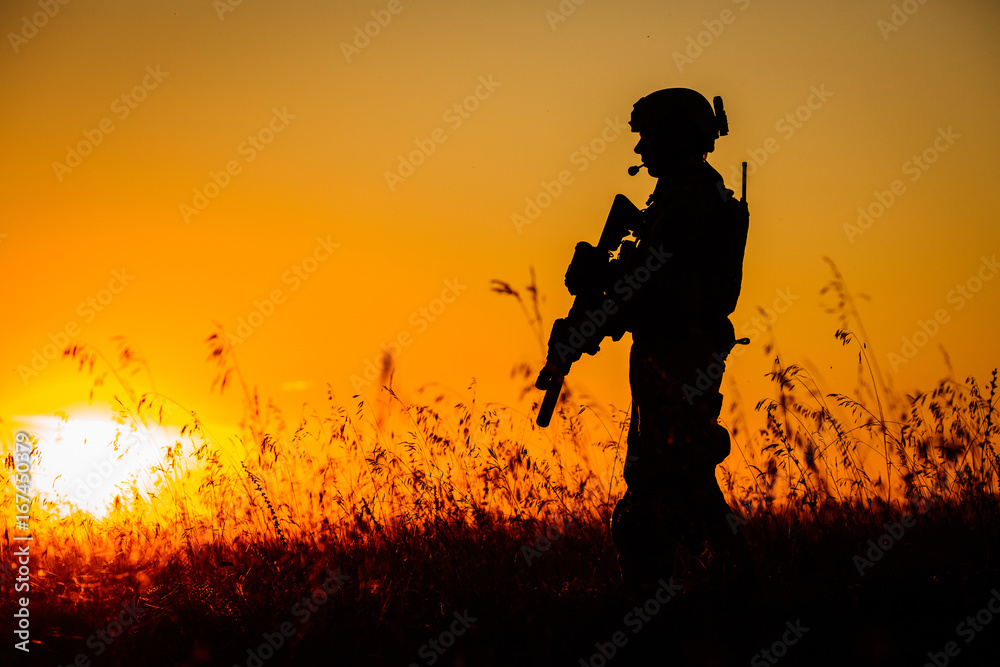 Silhouette of military soldier with weapons at sunset. shot, holding gun, colorful sky. military concept.