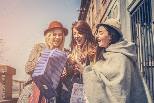 Girl shows her friends new clothes. Tree best friend enjoying in spring day.