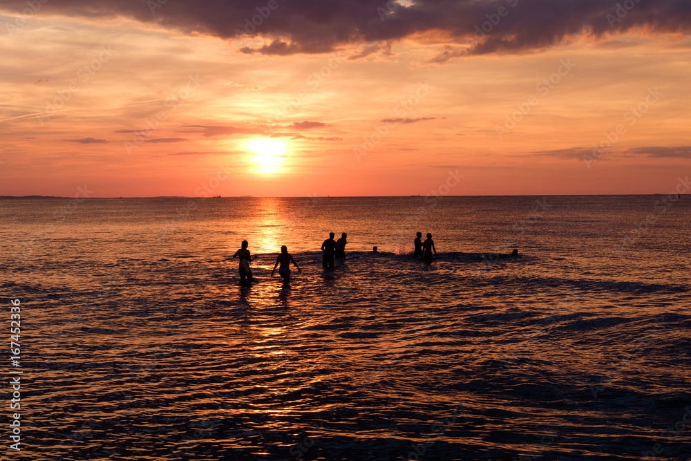silhouettes of people having fun in sea sunset background