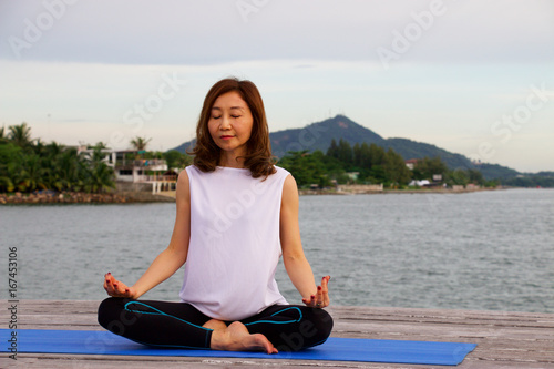 Woman is yoga and meditation at pier © thaninee