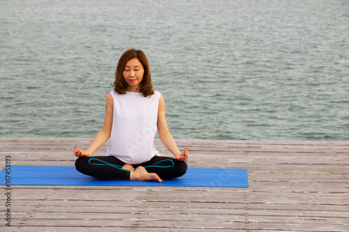 Woman is yoga and meditation at pier