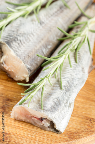 Fresh raw hake with rosemary branches in closeup macro view
