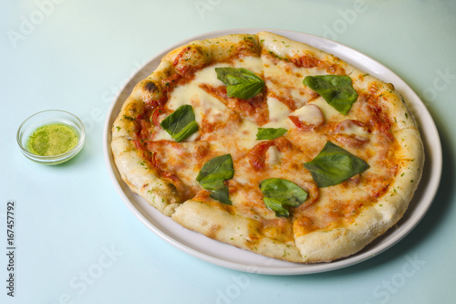 Pizza margarita on a white plate and blue background