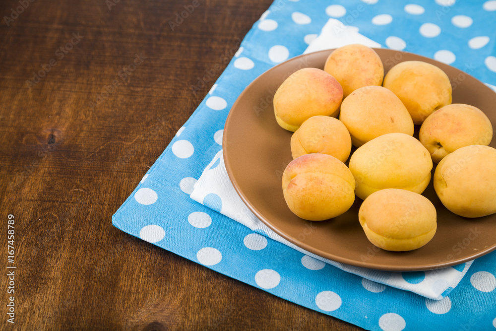 Apricots in a plate on a wooden table