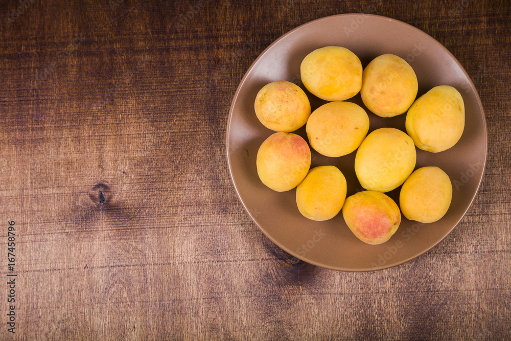 Apricots in a plate on a wooden table