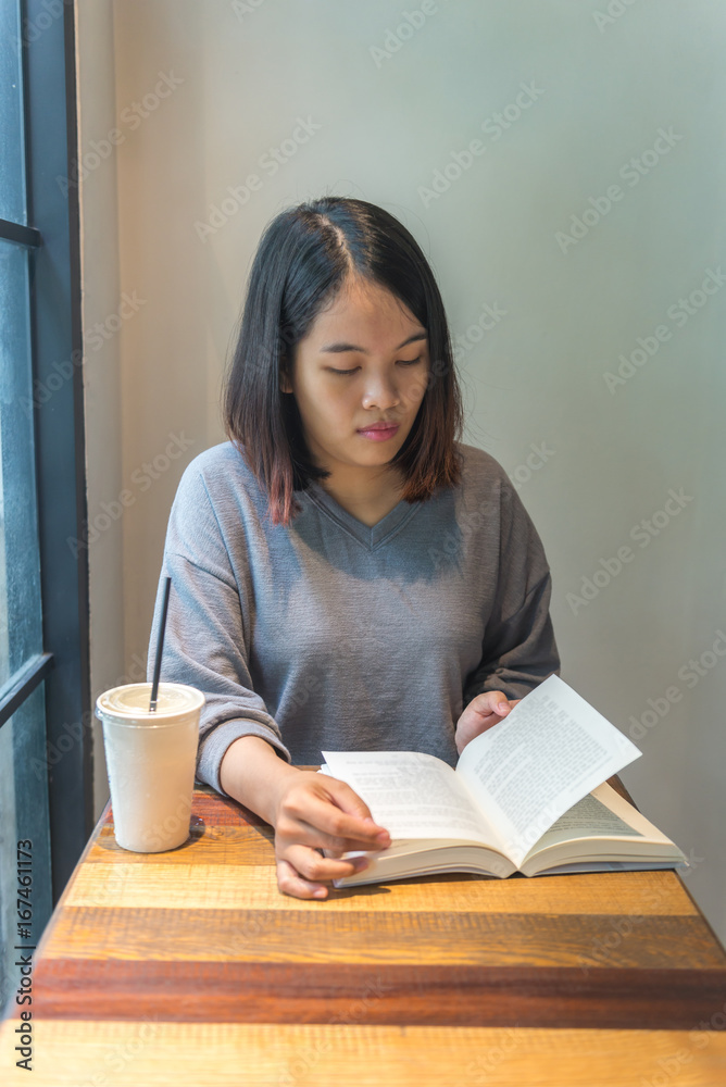 Naklejka premium Young female reading a book at the library