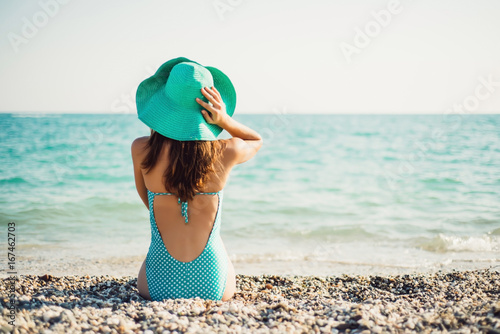 Wallpaper Mural Woman in a hat and a swimsuit in polka-dot sits on the shore and looks at the sea Torontodigital.ca