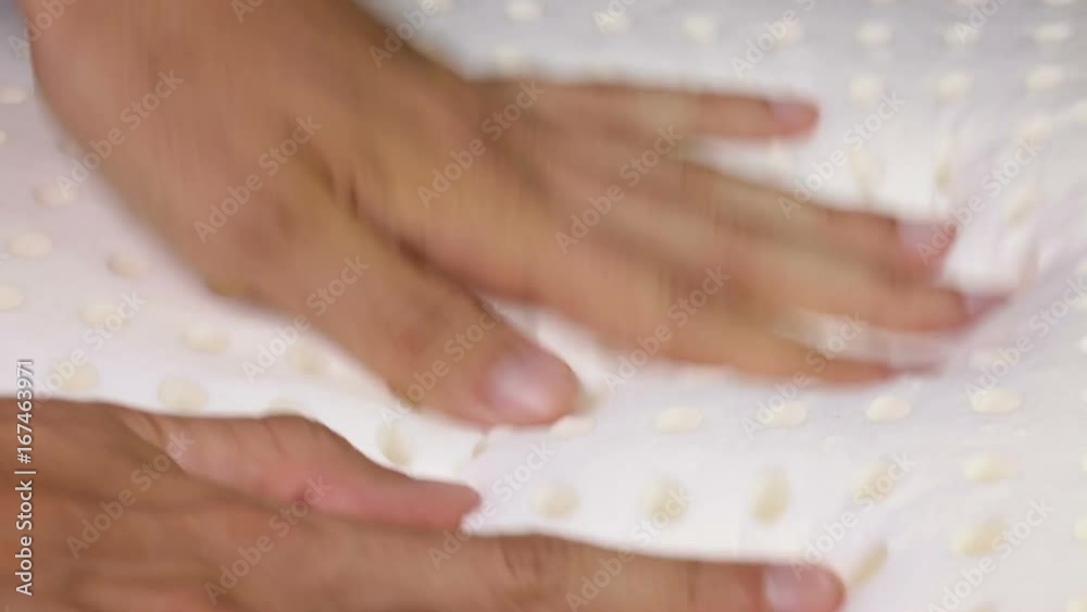 Mani di un uomo che stanno toccando un materasso in memory foam per testare la sua efficacia.