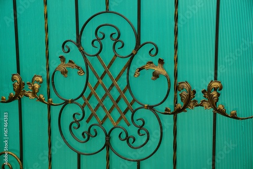 фрагмент  зелёных дверей с кованными прутьями и красивым узором