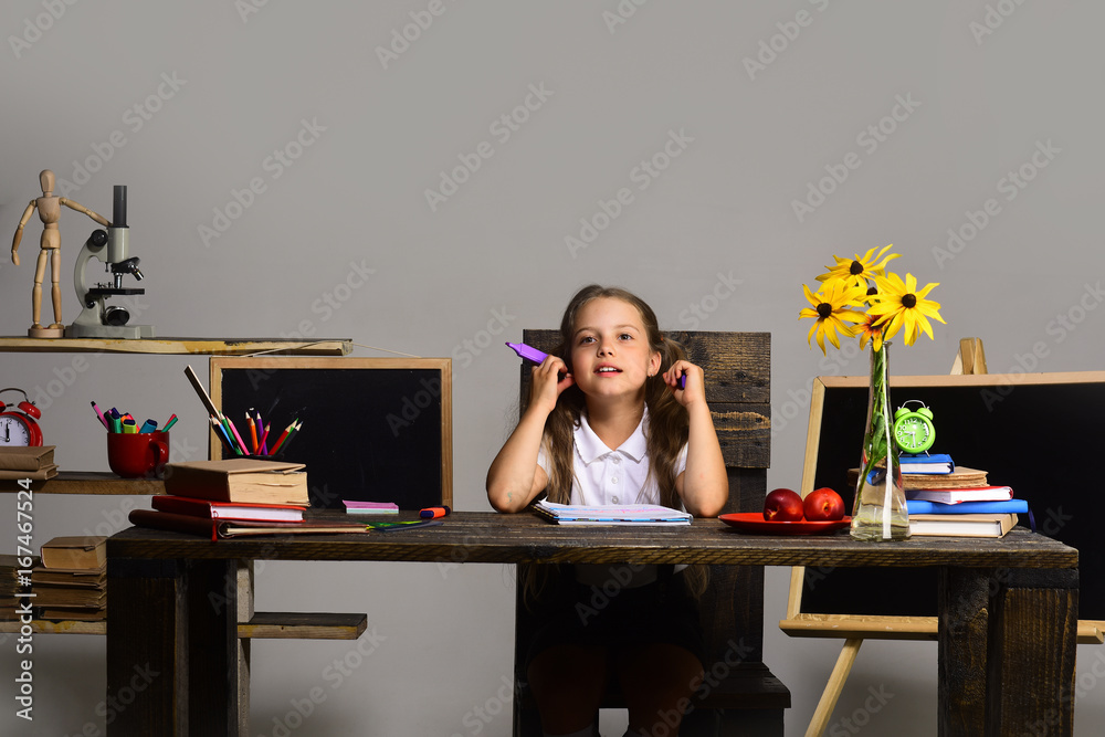 Kid and school supplies on grey wall background Kid and school supplies on grey wall background