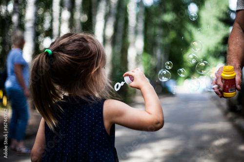 Baby blowing bubbles in a park