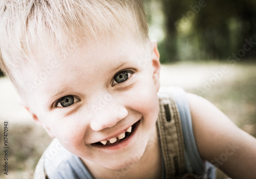 Portrait of a happy little boy in a summer park.