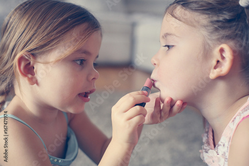 Cute little girls playing with make up in the room.