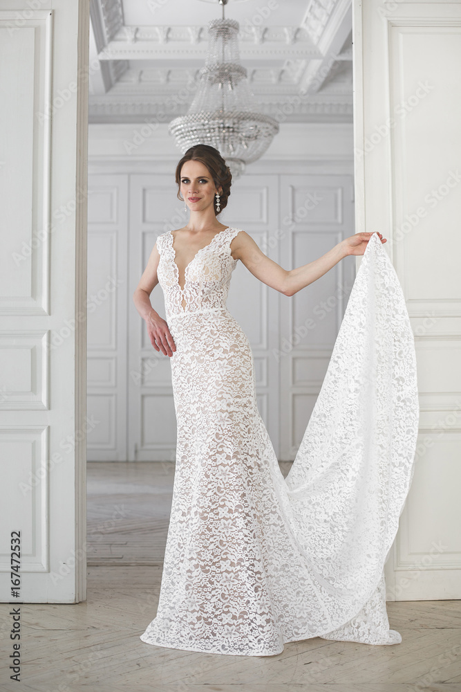 Beautiful bride posing in wedding dress in a white photo Studio. Mirror. Sofa. Bouquet. The door. Chandelier. Beautiful bride posing in wedding dress in a white photo Studio. Mirror. Sofa. Bouquet. The door. Chandelier.