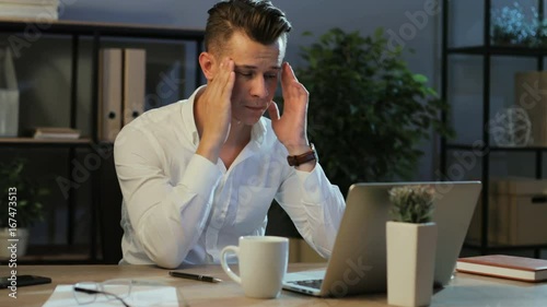 Portrait of young business man in casual shirt try working with anoying head ache in the laptop in the stylish office. photo