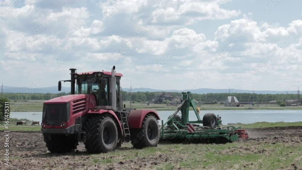Tractor driving on a countryside road in field near a lake Tractor driving on a countryside road in field near a lake