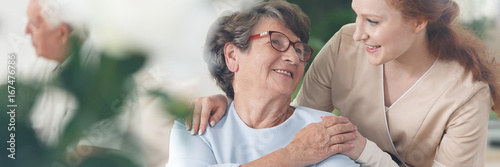 Caregiver comforting smiling senior woman