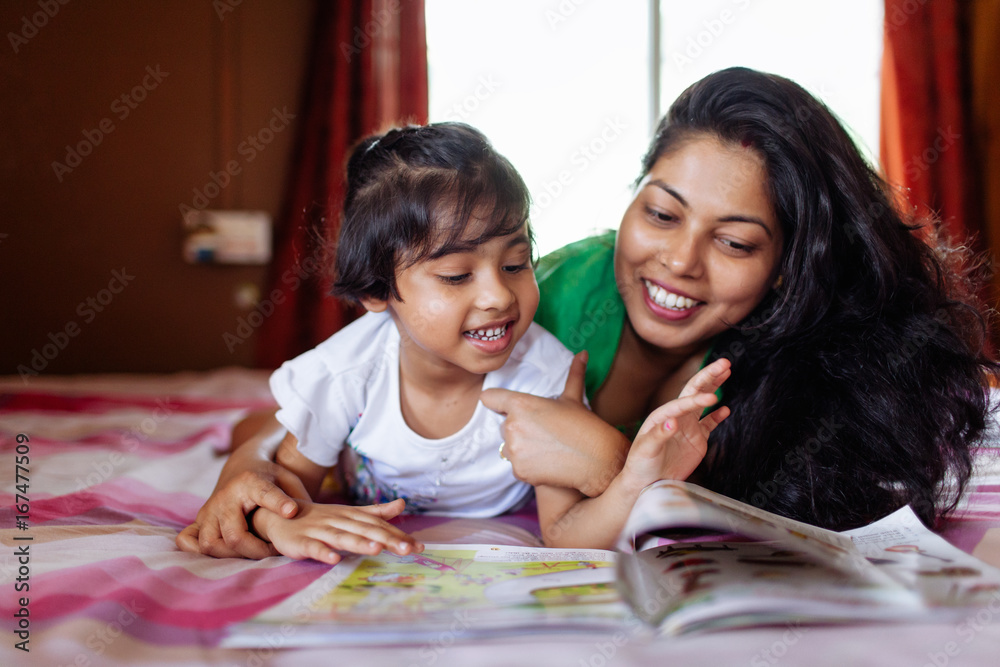 Little girl sharing a cheerful moment with her mother while studying Little girl sharing a cheerful moment with her mother while studying