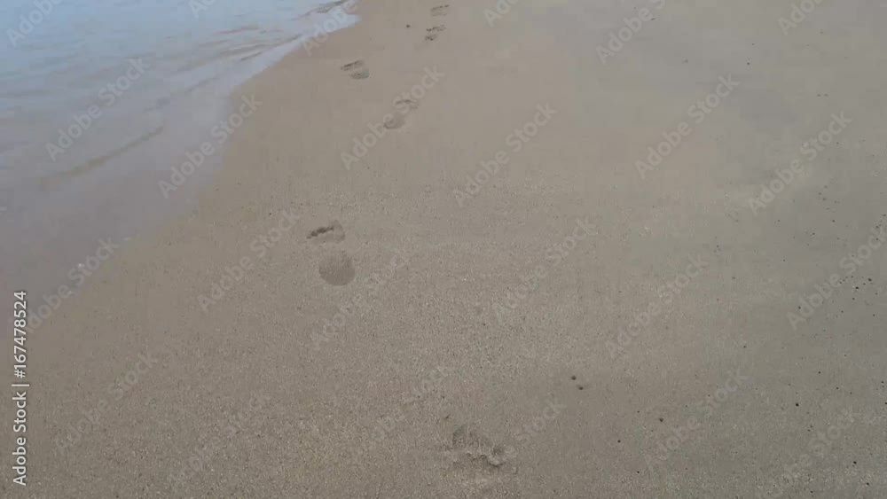 Steps baby on the beach barefoot.