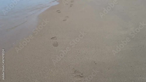 Steps baby on the beach barefoot.