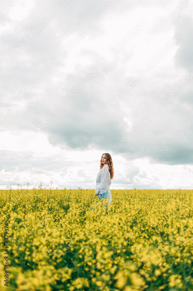 Beautiful girl in a dress among yellow flowers in a field Beautiful girl in a dress among yellow flowers in a field