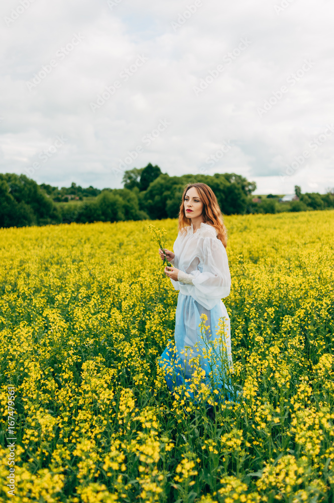 Beautiful girl in a dress among yellow flowers in a field Beautiful girl in a dress among yellow flowers in a field