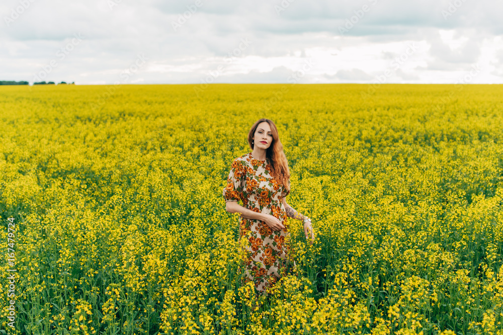 Beautiful girl in a dress among yellow flowers in a field Beautiful girl in a dress among yellow flowers in a field
