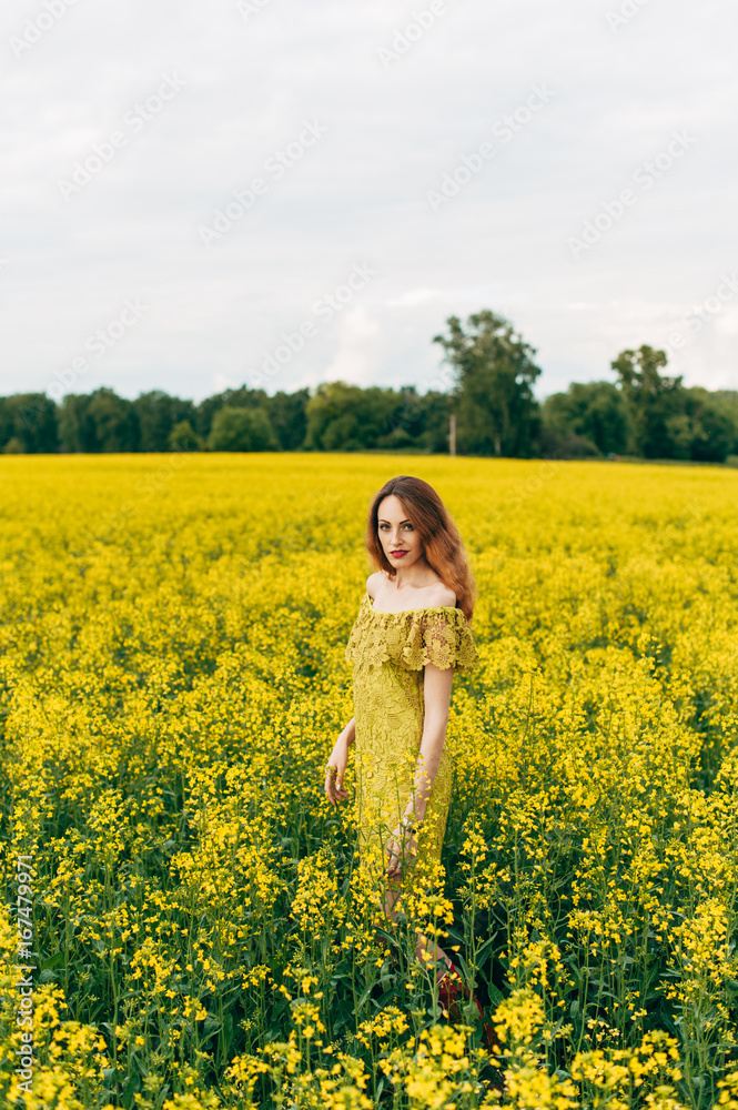 Beautiful girl in a dress among yellow flowers in a field Beautiful girl in a dress among yellow flowers in a field