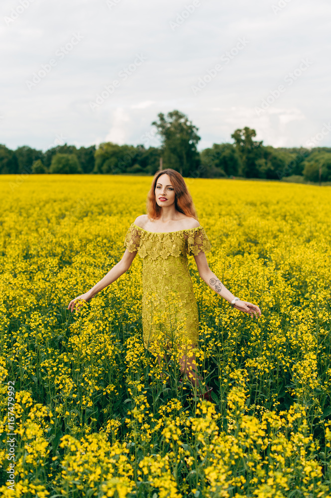Beautiful girl in a dress among yellow flowers in a field Beautiful girl in a dress among yellow flowers in a field
