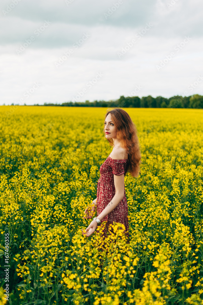 Beautiful girl in a dress among yellow flowers in a field Beautiful girl in a dress among yellow flowers in a field