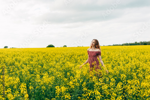 Beautiful girl in a dress among yellow flowers in a field