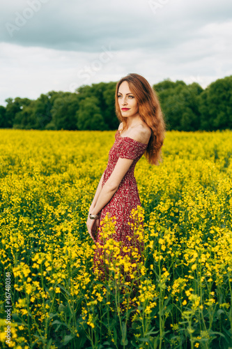 Beautiful girl in a dress among yellow flowers in a field