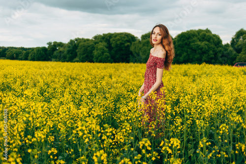 Beautiful girl in a dress among yellow flowers in a field