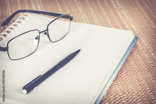 Pen and glasses with blank diary. Vintage effect tone.