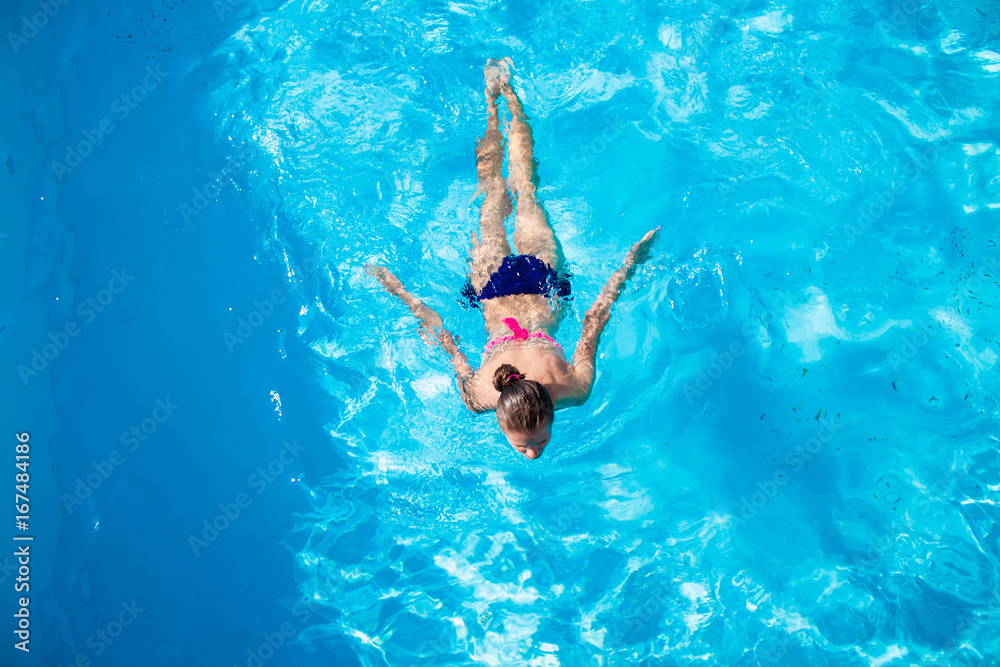 Top view of a girl diving in the swimming pool. Summer day