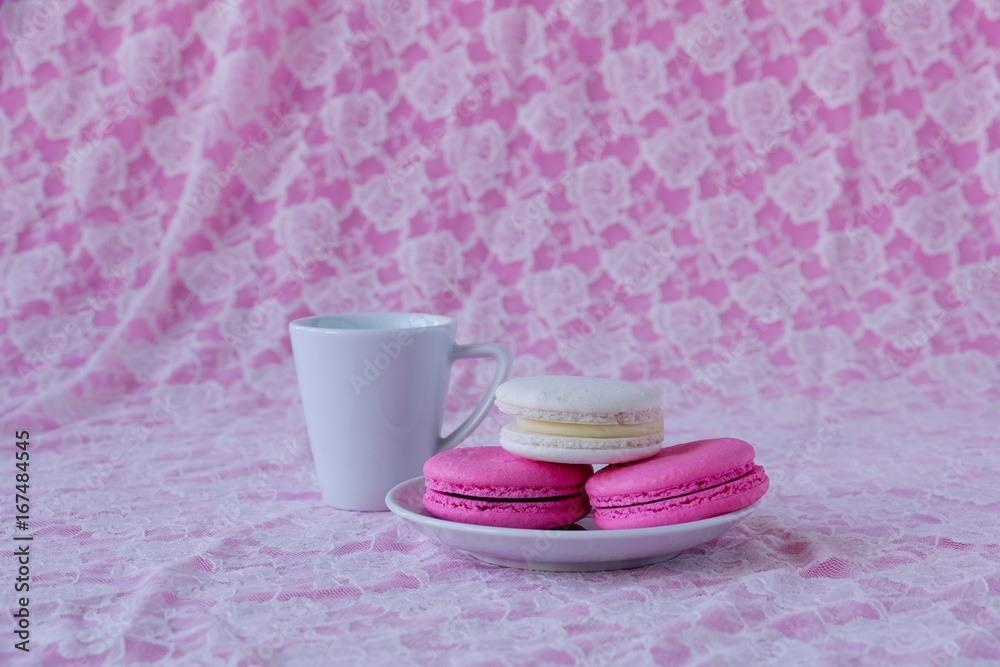 Colorful macaroons on plate and cup of coffee on white lace Colorful macaroons on plate and cup of coffee on white lace