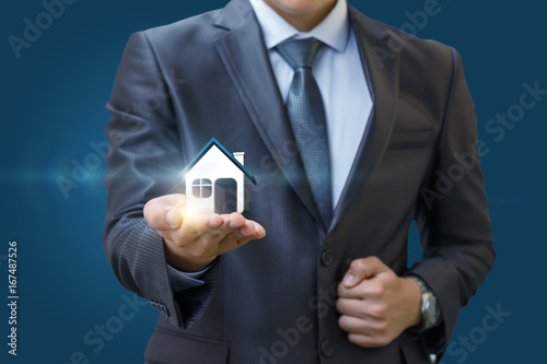 Real estate agent holding a model house in hand .