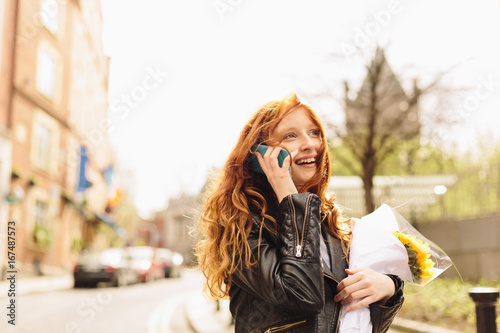 Young Girl on the Phone Talking and Holding Flowers photo