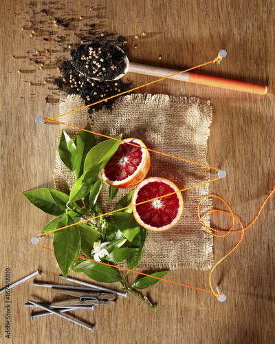 Still life of cut grapefruit and leaves with seeds on warm wood surface photo