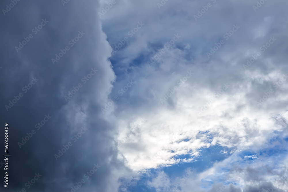 Bright blue sky and white cloud peek out from clearance in grey dark clouds. Bright blue sky and white cloud peek out from clearance in grey dark clouds.
